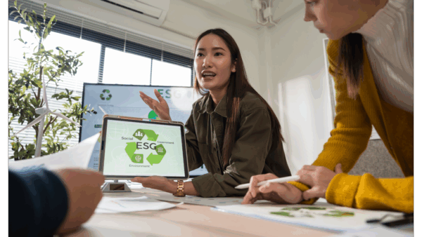 Colleagues collaborating on an eco-focused job, viewing a monitor with a recycling symbol
